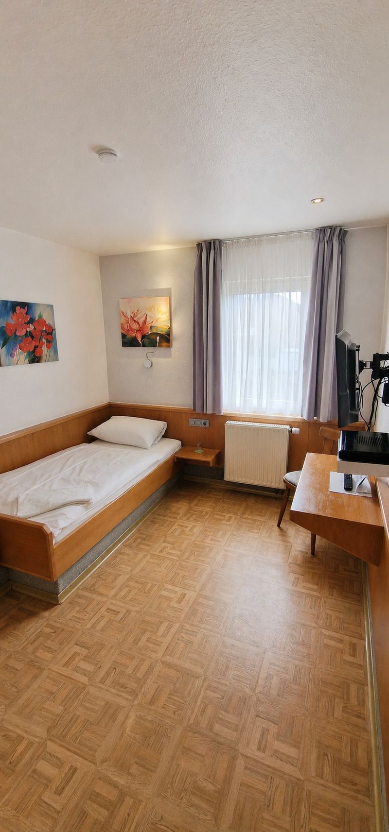 Einzelzimmer mit Bett, Schreibtisch, Fernseher und Fenster im Hotel Zum Goldenen Hahnen